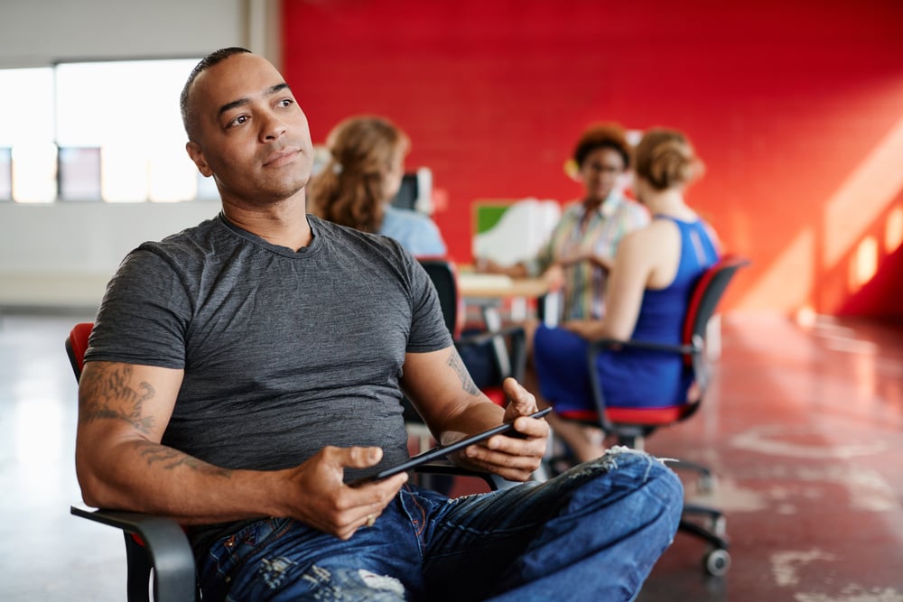 Confident male designer working on a digital tablet in red creative office space-2